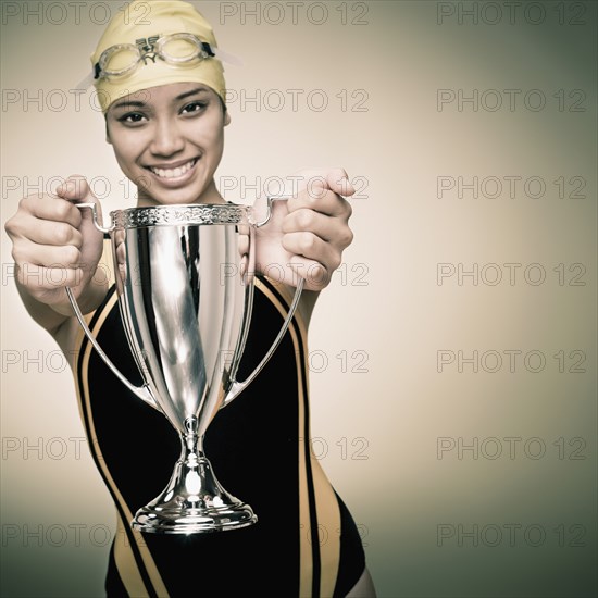 Mixed race swimmer holding trophy