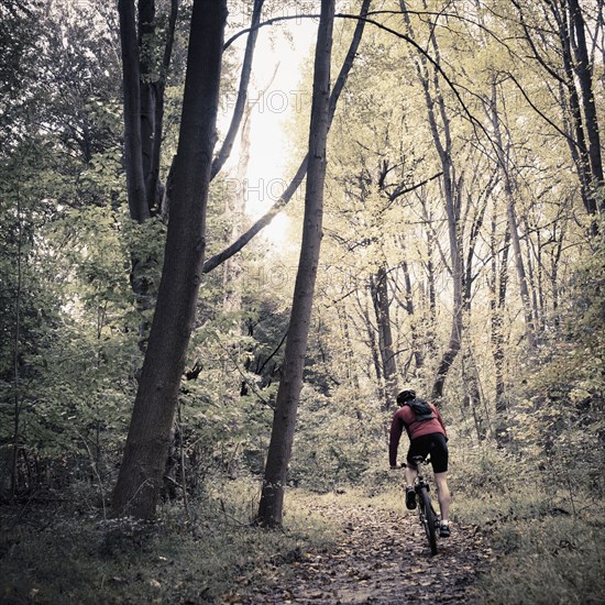 Caucasian man riding mountain bike in forest