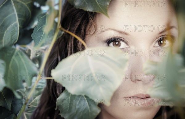 Native American woman peering through leaves