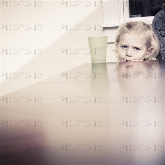 Caucasian girl peering over table