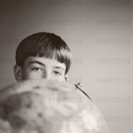 Boy peering over globe