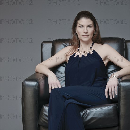 Mixed race woman in evening gown sitting in armchair