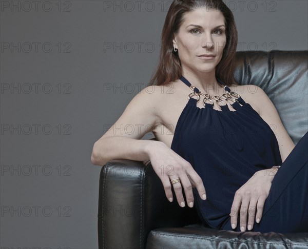 Mixed race woman in evening gown sitting in armchair