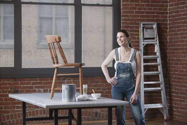 Mixed race woman painting chair in loft