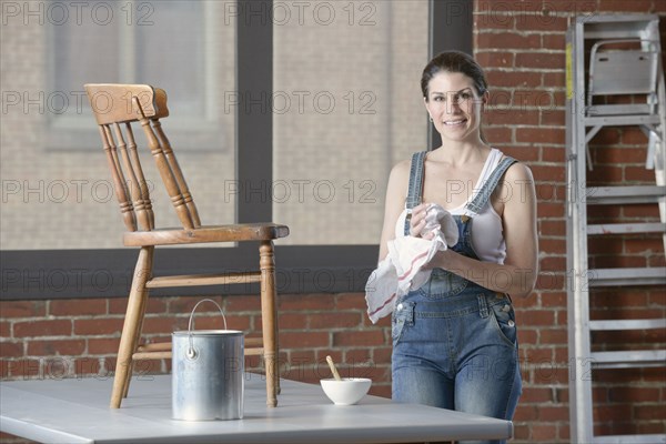 Mixed race woman painting chair in loft