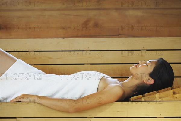 Asian woman relaxing in sauna
