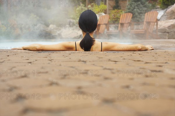 Rear view of woman sitting in hot tub