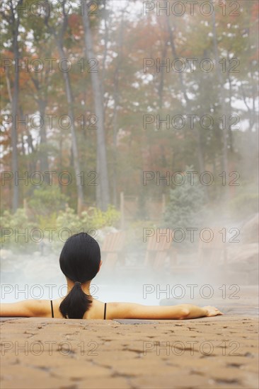 Rear view of woman sitting in hot tub