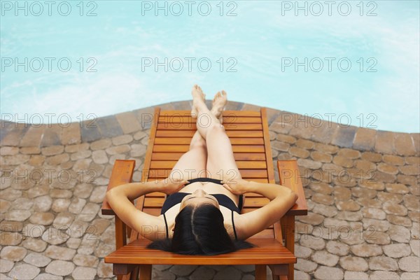 Woman sunbathing next to swimming pool