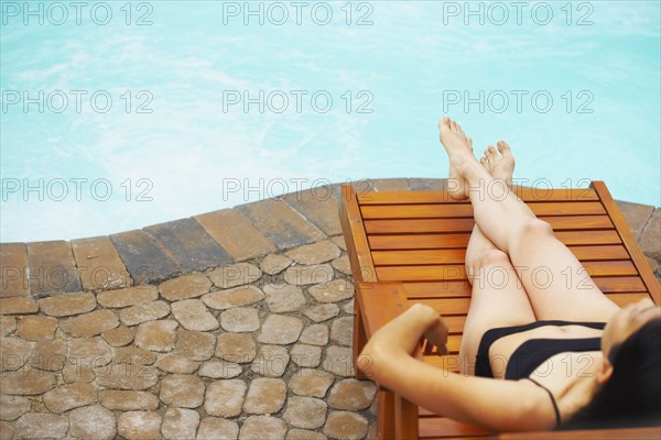 Woman sunbathing next to swimming pool