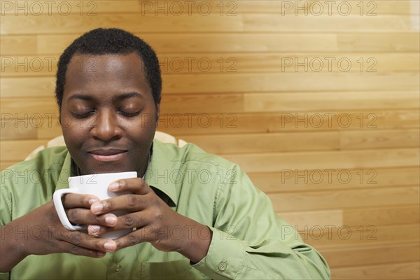 African man smelling cup of coffee