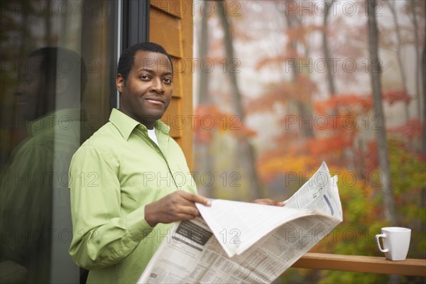 African man reading newspaper outdoors
