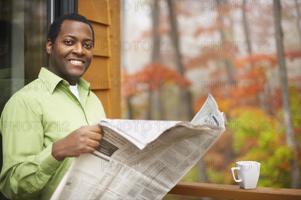 African man reading newspaper outdoors