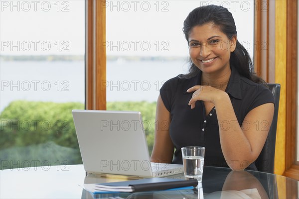 Indian woman at table with laptop