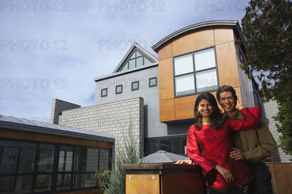 Couple hugging in front of modern house