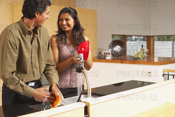 Couple washing dishes in kitchen