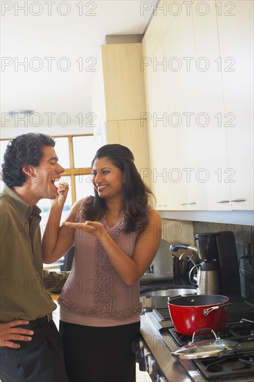 Woman feeding husband in kitchen