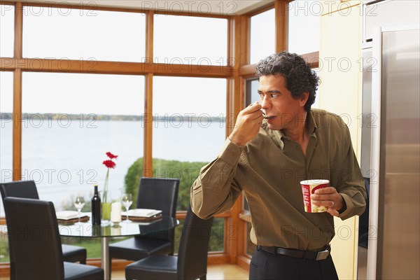 Man eating ice cream next to refrigerator