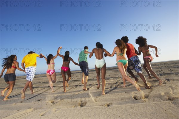 Multi-ethnic group of friends running on beach