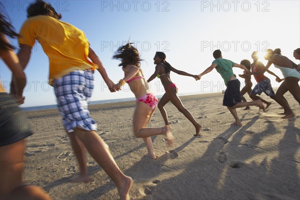 Multi-ethnic group of friends running on beach