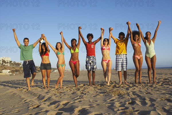 Multi-ethnic group of friends cheering on beach