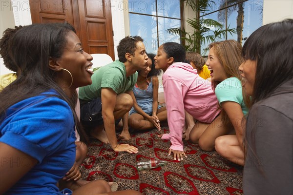 Multi-ethnic group of friends playing spin the bottle