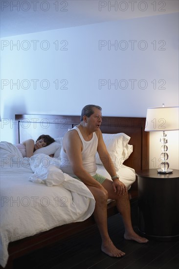 Man in bedroom waking up in the morning