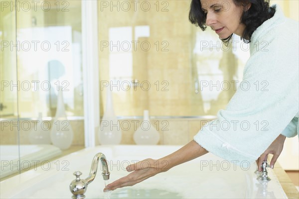 Smiling Middle Eastern woman checking water temperature in spa