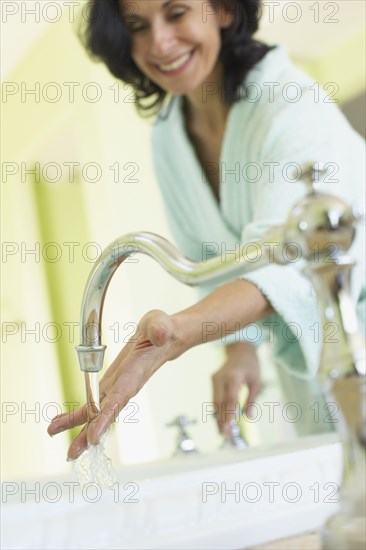 Smiling Middle Eastern woman checking water temperature in spa