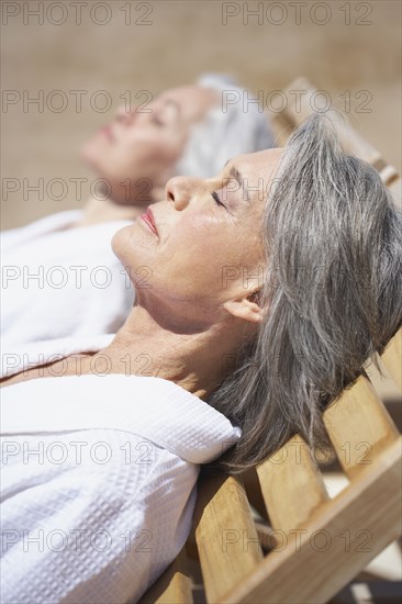 Friends sleeping on lounge chairs at resort