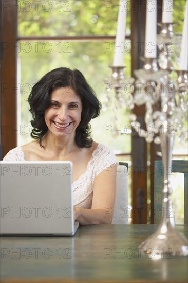 Confident Middle Eastern woman typing on laptop in dining room