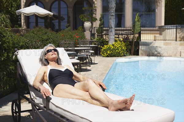 Woman at poolside laying on lounge chair