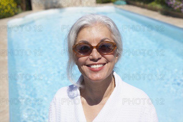 Woman at poolside in bathrobe and sunglasses