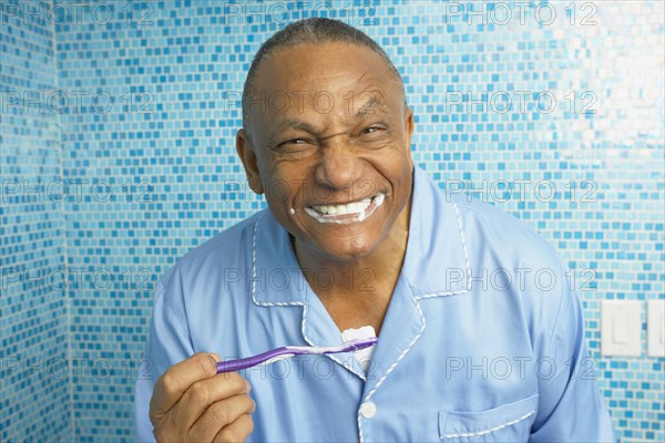 African man brushing his teeth in bathroom