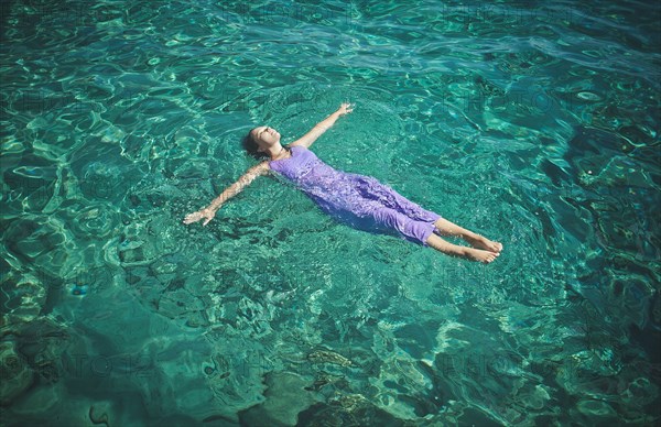 Caucasian woman wearing dress floating in water