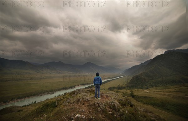 Caucasian boy standing near river in cloudy landscape