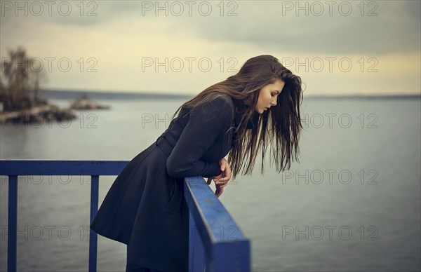 Caucasian woman leaning on railing at waterfront