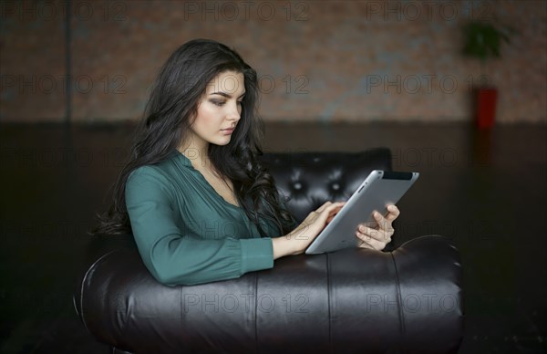 Caucasian businesswoman sitting on sofa using digital tablet