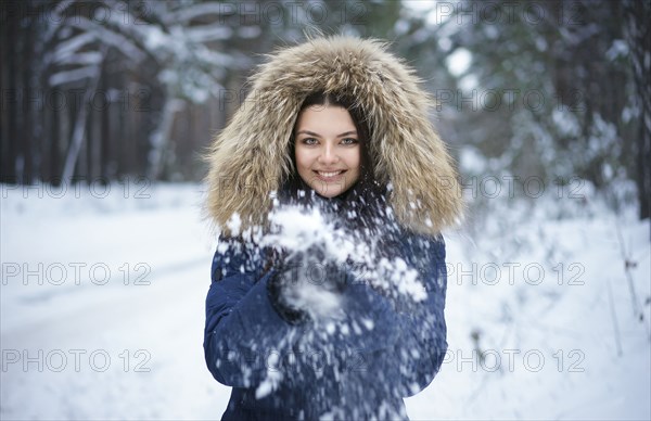 Portrait of playful Caucasian woman throwing snow