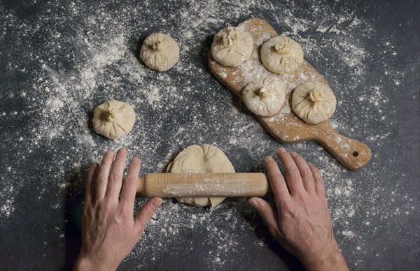 Hands of Caucasian man using rolling pin on dough