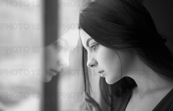 Caucasian woman leaning forehead on window