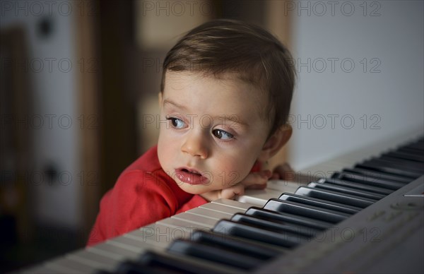 Curious boy leaning on piano