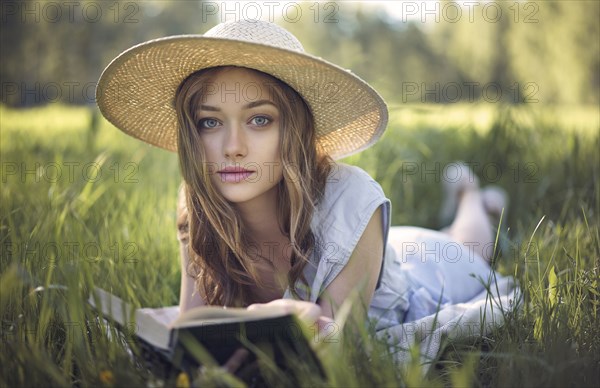 Caucasian woman laying in grass reading book