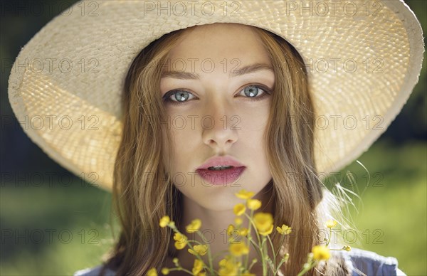 Caucasian woman wearing hat holding wildflowers