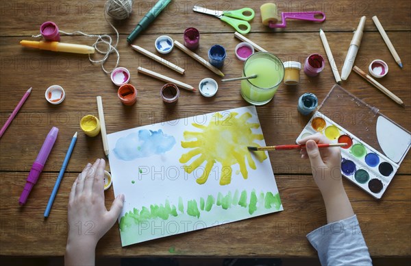 Hands of Caucasian boy painting with watercolors