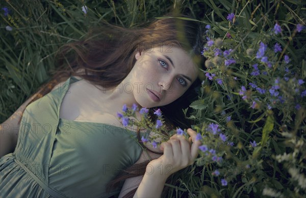 Caucasian woman laying in grass with wildflowers