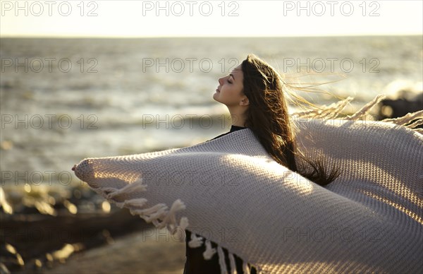 Wind blowing shawl of Caucasian woman at beach