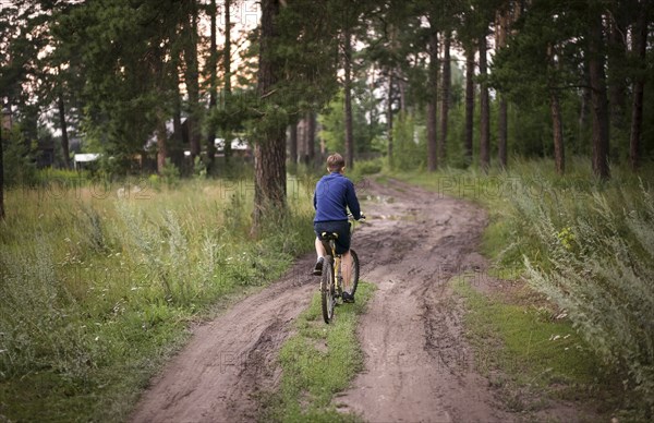 Caucasian teenage boys riding bicycle in woods