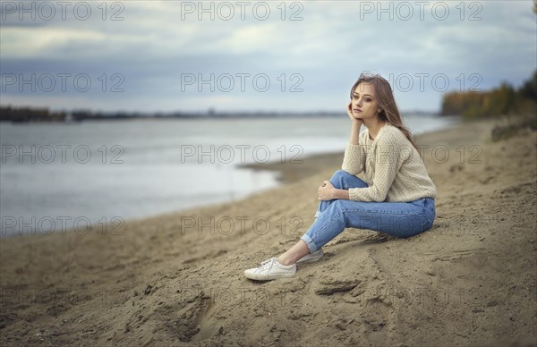 Pensive woman sitting on beach