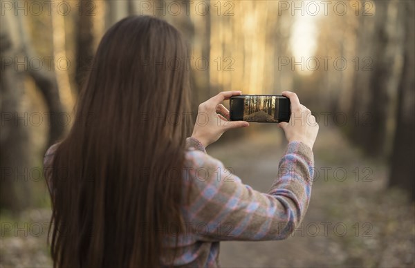 Caucasian woman photographing path with cell phone